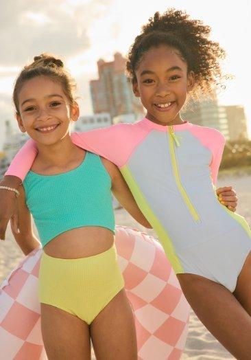 Two young girl models wearing one-piece swimsuits.