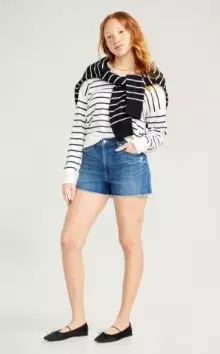 A woman in denim shorts and striped shirt.