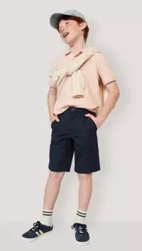 A male model wears dark chino shorts and light colored t-shirt.