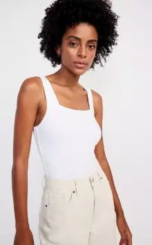 A female model wearing a white square neck tank top.