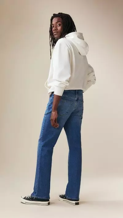 A male model wearing straight jeans and a beige jacket.