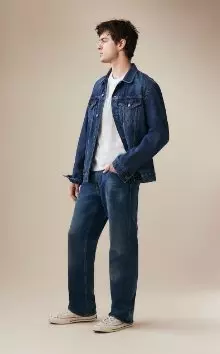 A male model wearing loose jeans and a jean jacket.