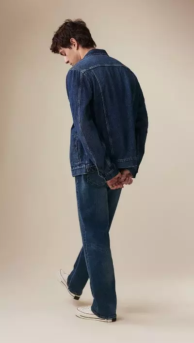 A male model wearing loose jeans and a jean jacket.