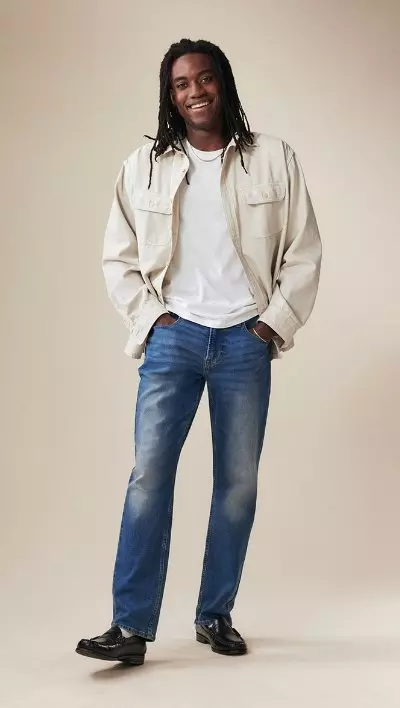 A male model wearing straight jeans and a beige jacket.