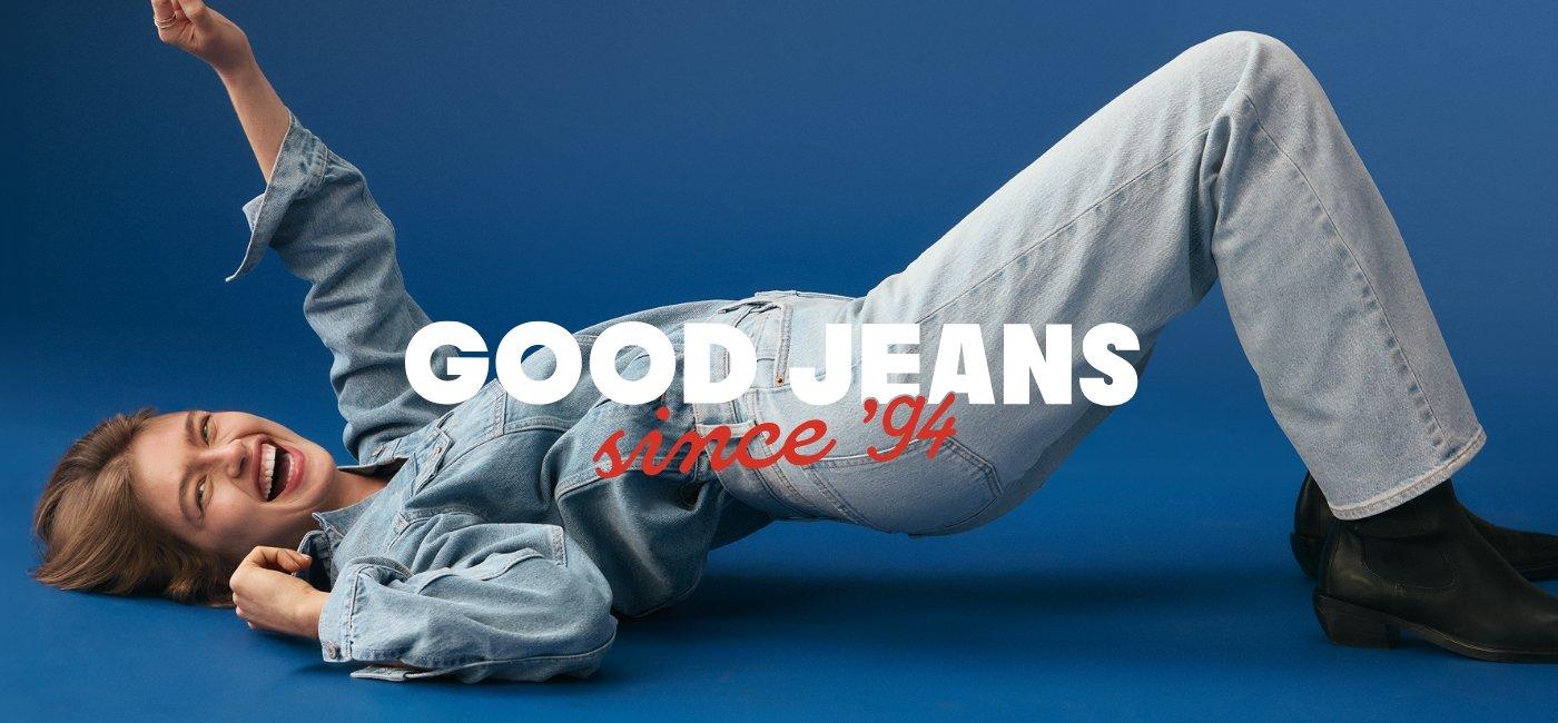 Image displays a female model wearing jeans and jean jacket and laying down. Good jeans since '94.