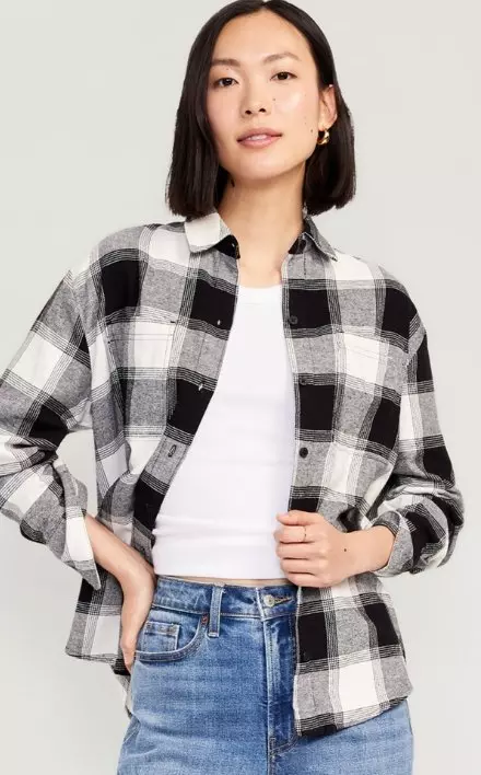 A woman in a grey and cream flannel paired with a white tank and jeans.