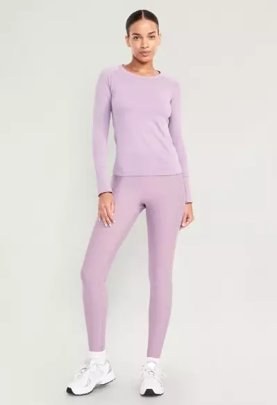 A female model wears a long-sleeve crew neck activewear top.