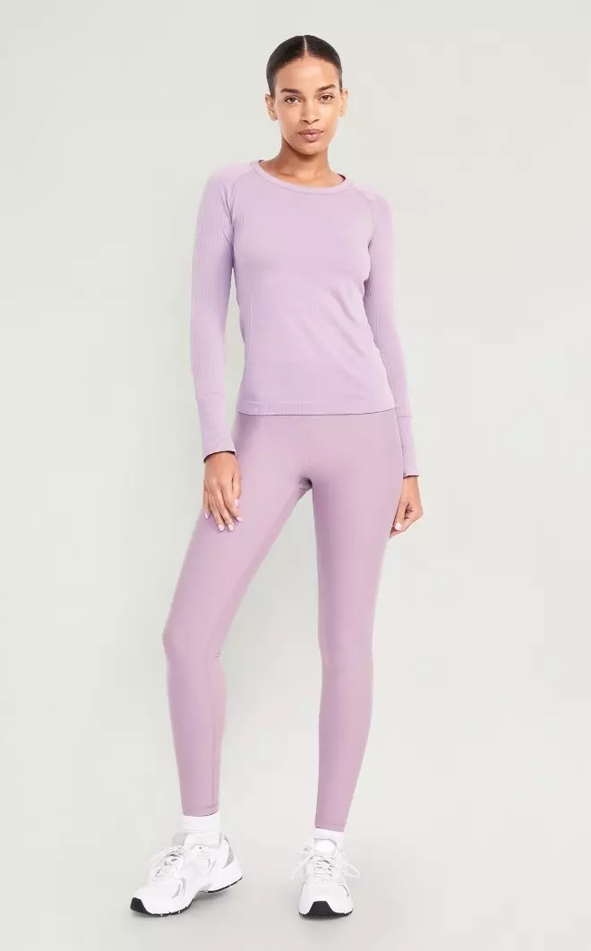 A female model wears a long-sleeve crew neck activewear top.