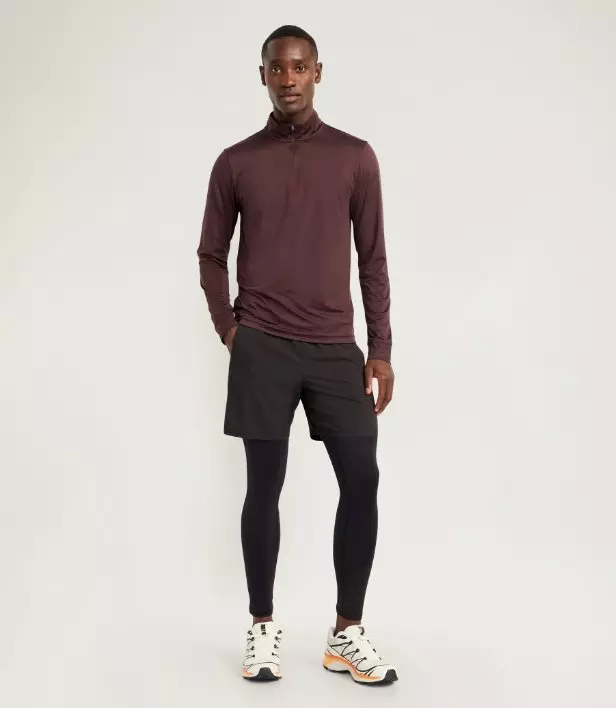 A male model wears dark base layer legging with his maroon activewear outfit.