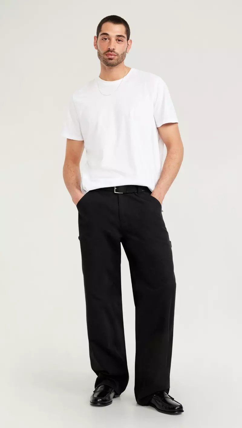 A male model wearing black baggy pants.