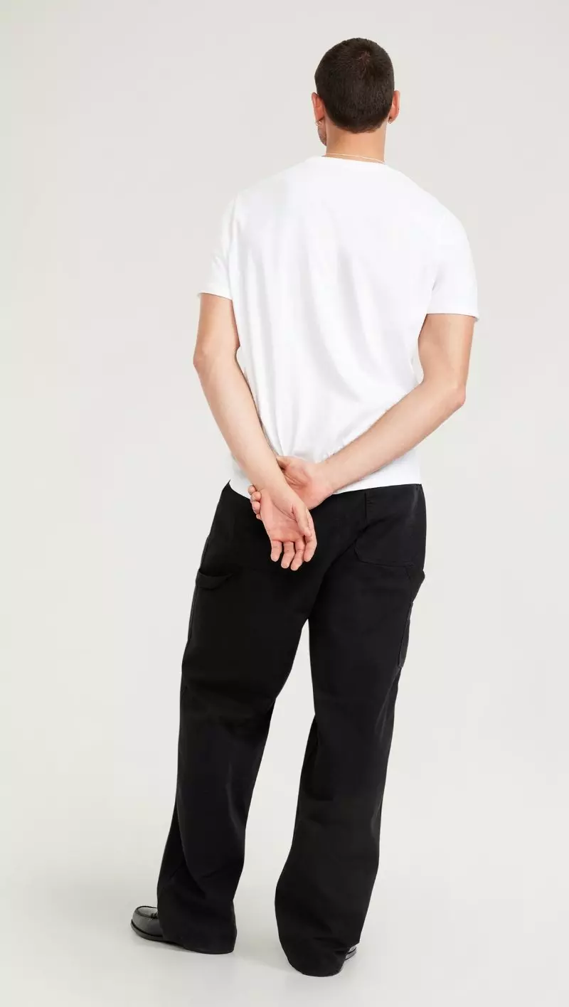 A male model wearing black baggy pants.