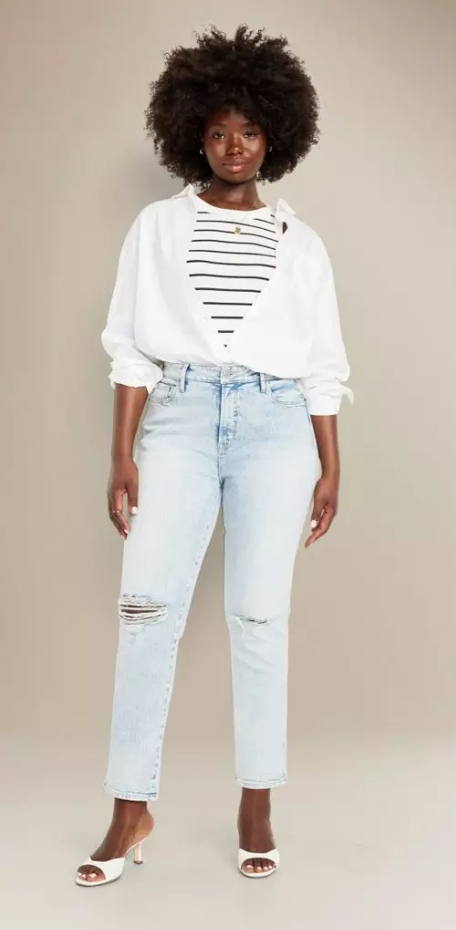 A woman in curvy fit light wash ripped jeans.