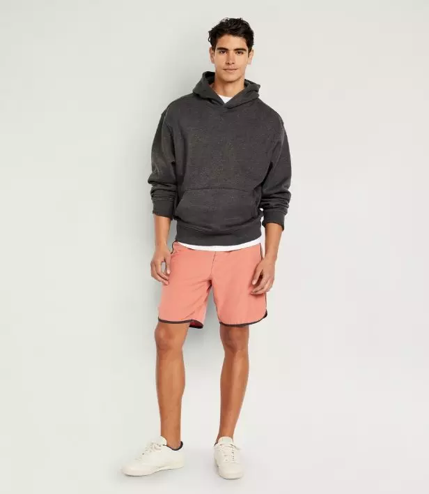 Model dressed in board shorts and a dark hoodie.