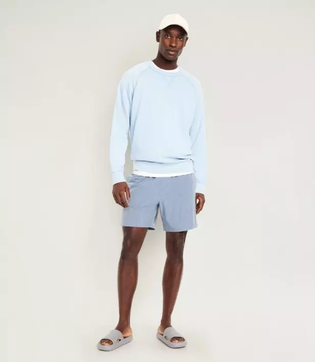 A model wearing hybrid swim shorts & a light coloured sweatshirt.