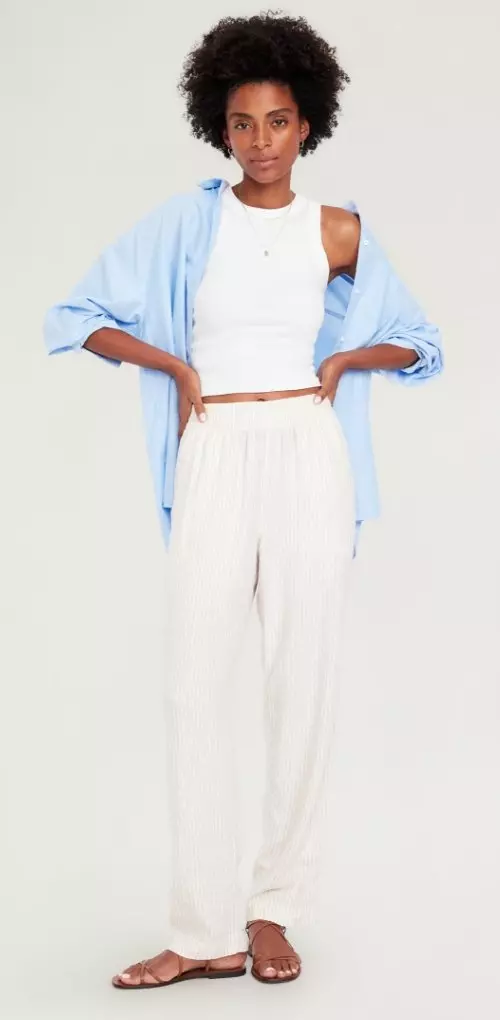 A woman dressed in straight leg cream color pants.