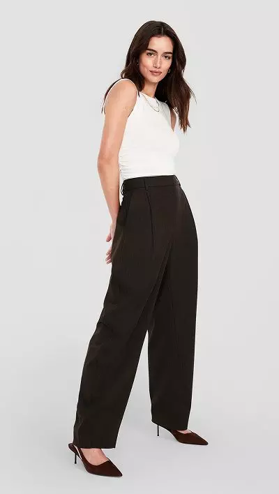 A woman dressed in barrel leg olive green pants.