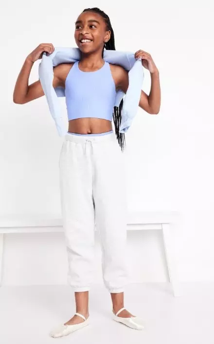 A young female model wears performance joggers and a crop top.