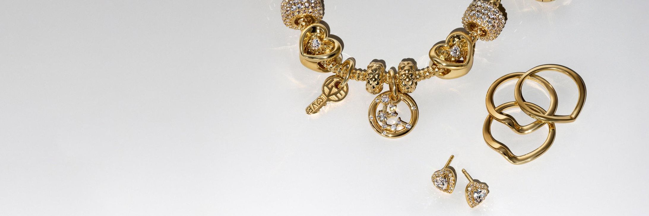 Immagine del bracciale con charm BE LOVE di Pandora in oro e diamanti di laboratorio e cinque orecchini