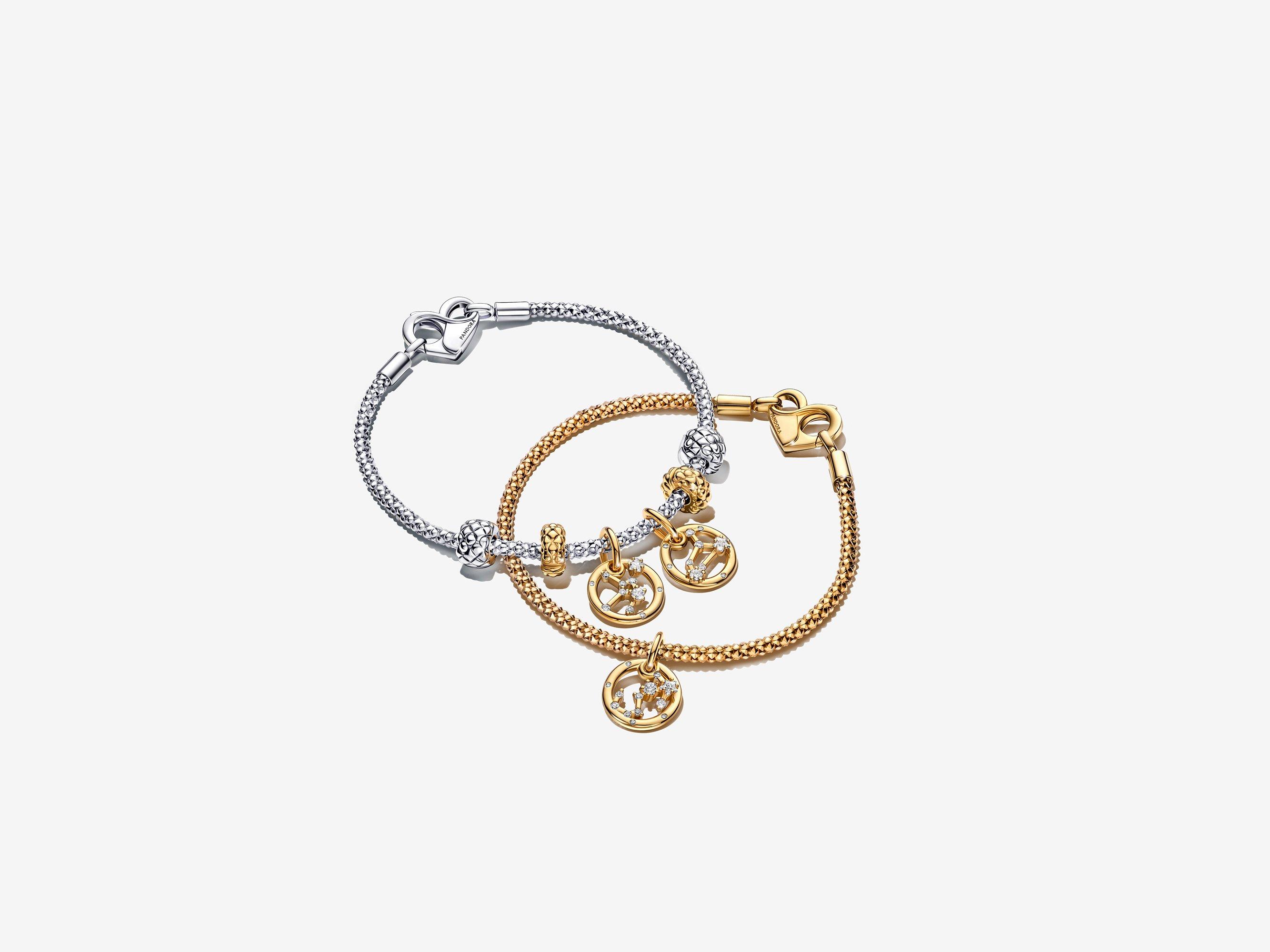 Image of a gold pandora moments zodiac charm bracelet on top of a silver bracelet