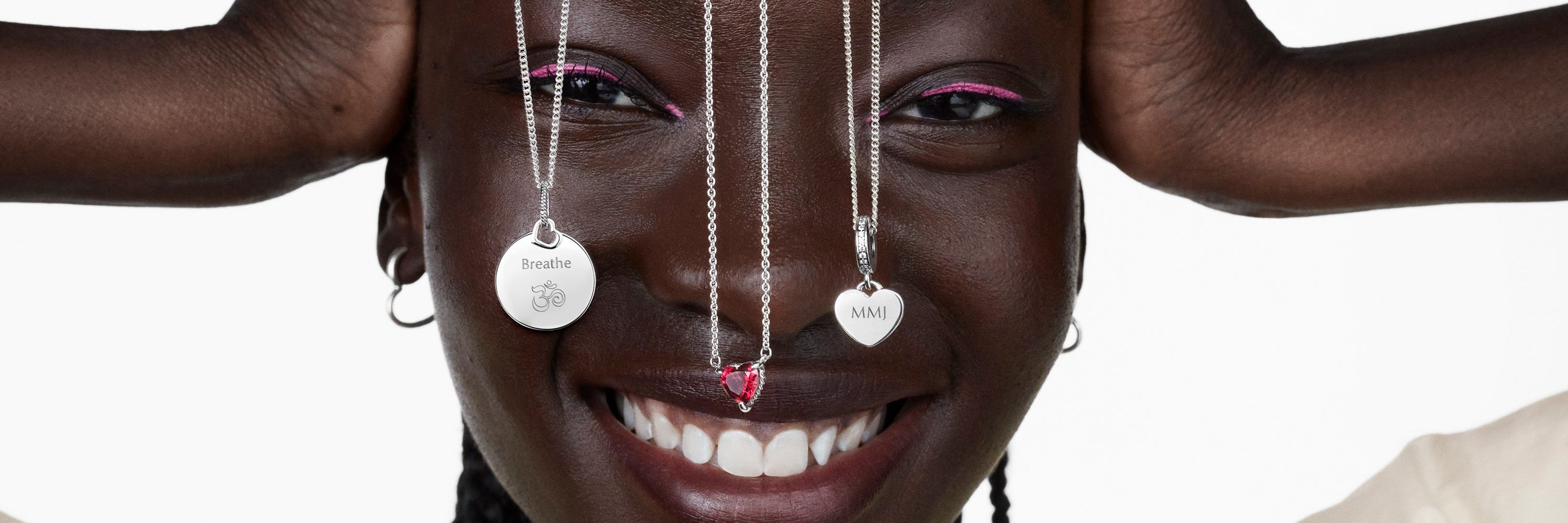 Femme souriante avec trois colliers Pandora en argent pendant au-dessus de son visage