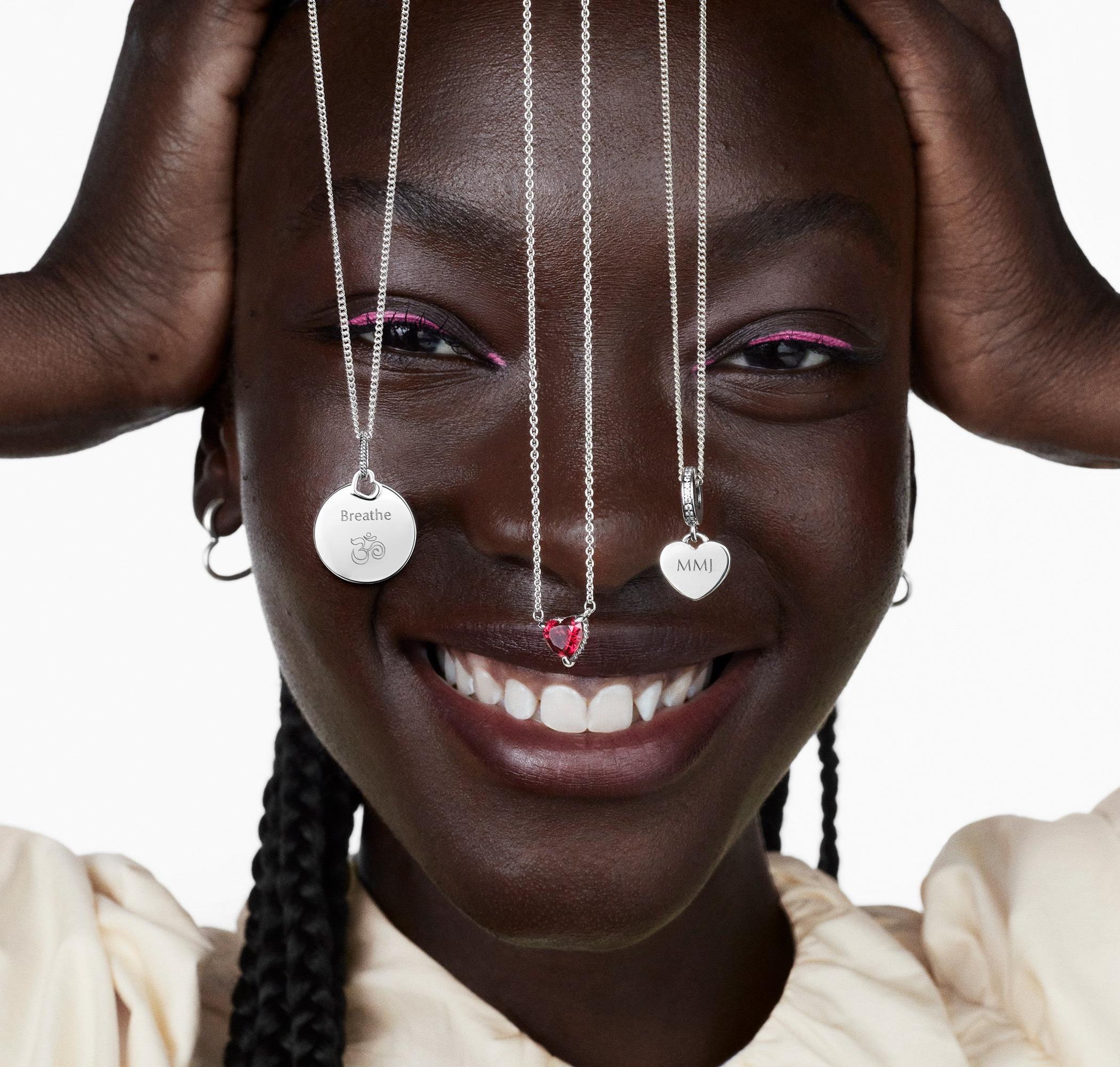 Woman smiling with three silver Pandora necklaces dangling over her face