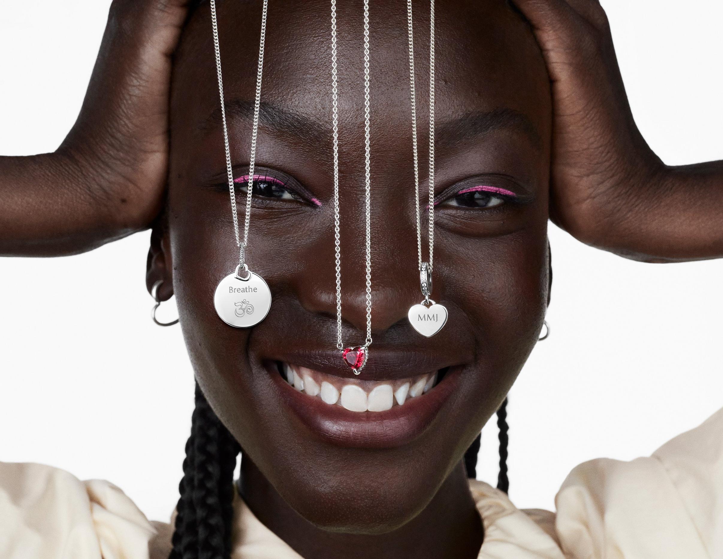 Femme souriante avec trois colliers Pandora en argent pendant au-dessus de son visage