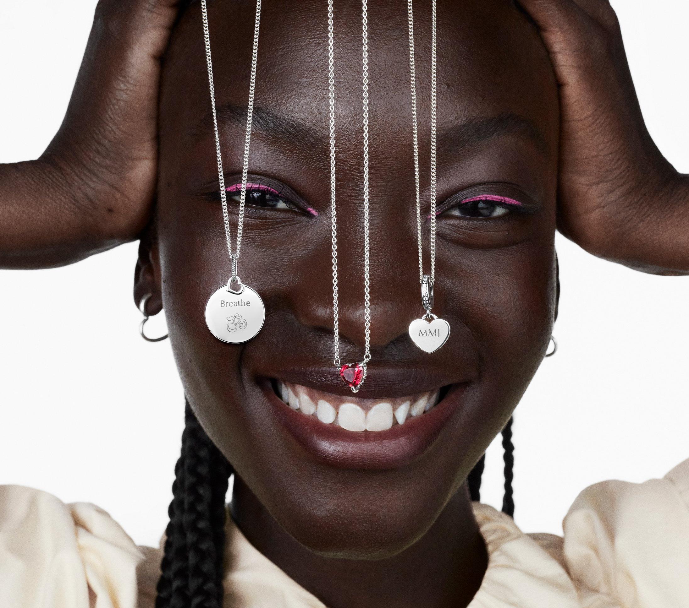 Woman smiling with three silver Pandora necklaces dangling over her face