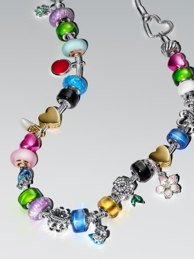 A colourful charm bracelet lays on a flat, white surface. The multi-coloured bracelet features blue, pink and gold charms.