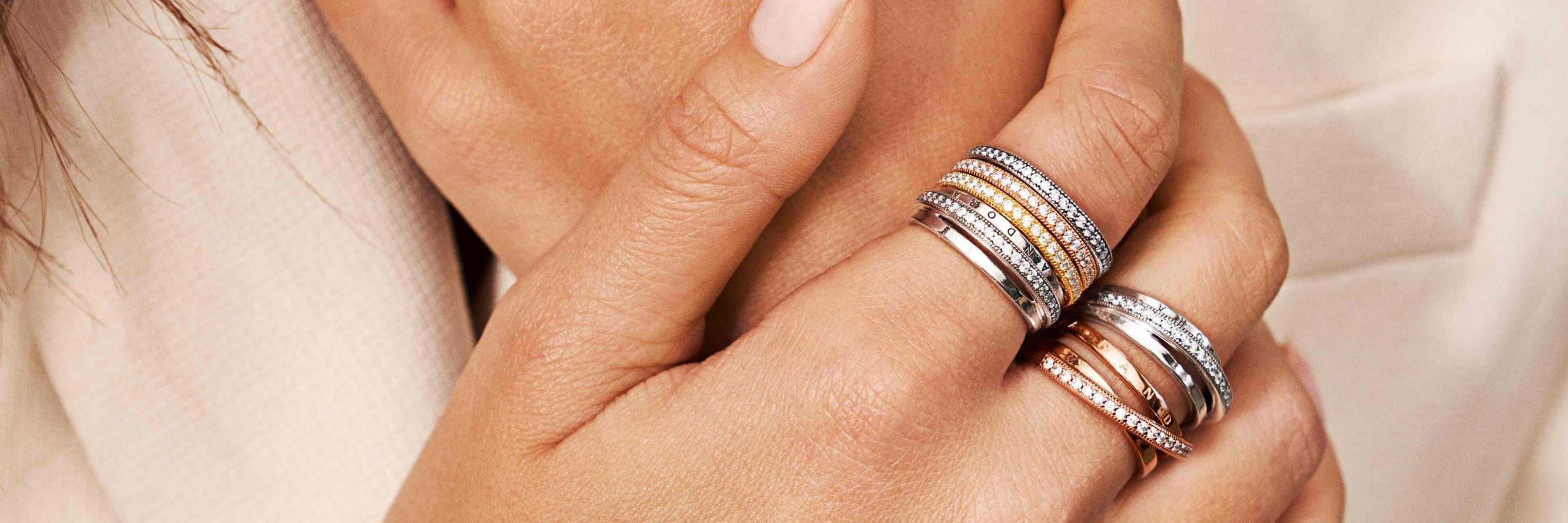 Les mains d'un mannequin portant des bagues empilables Pandora en argent et en Pandora Rose