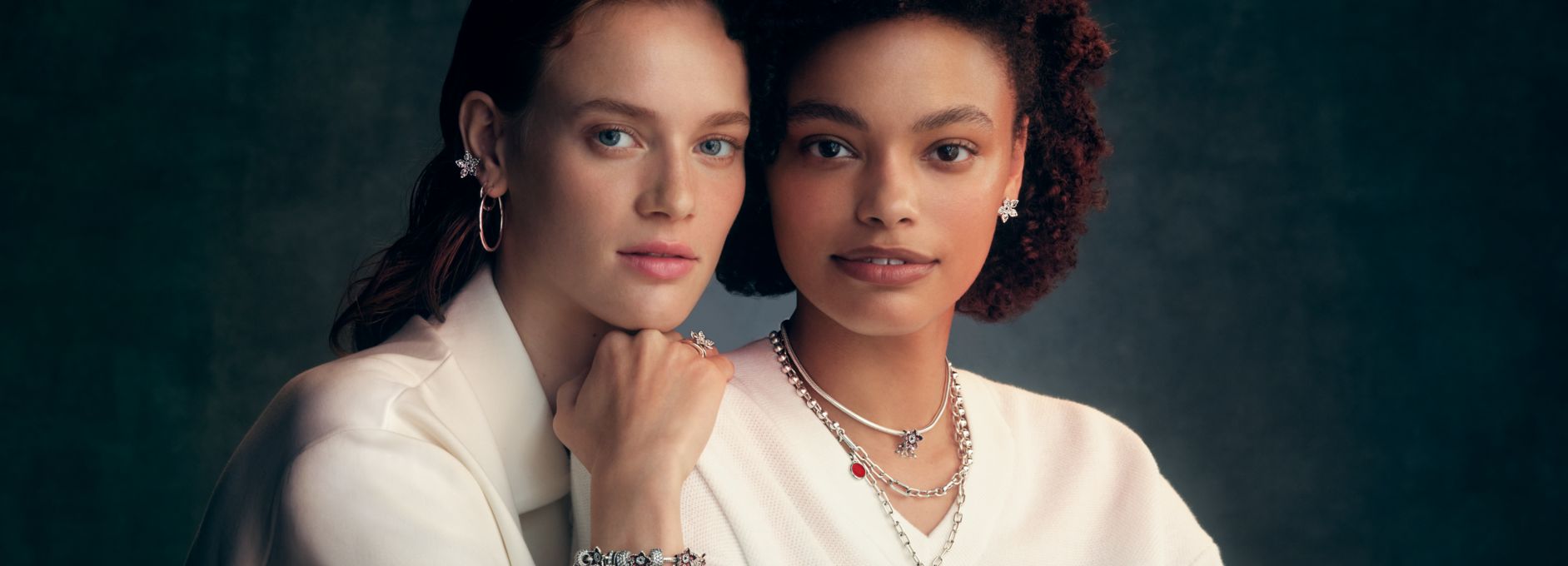 Two models wearing sterling silver pieces from the Stranger Things collection, including a necklace stack and charm bracelet.