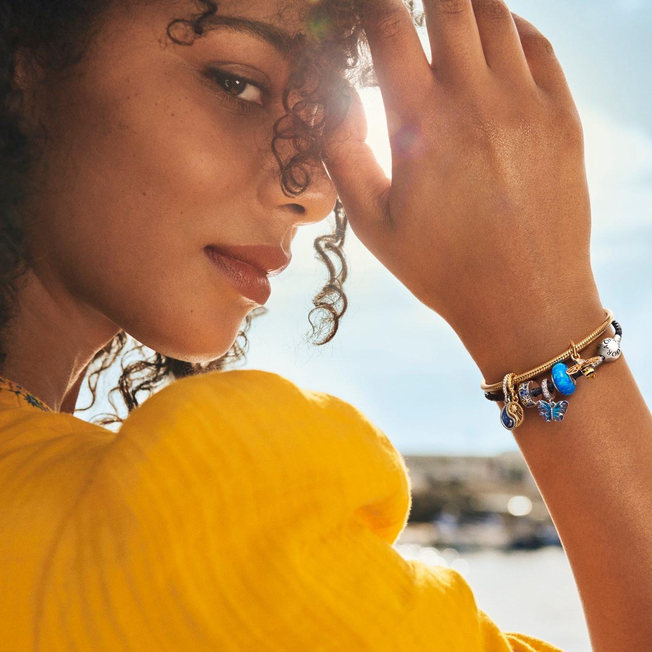 Smiling woman with colourful blue charms on bracelet.