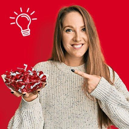 Woman Smiling holding a bowl of hersheys kisses with a Light Bulb Above Her Head