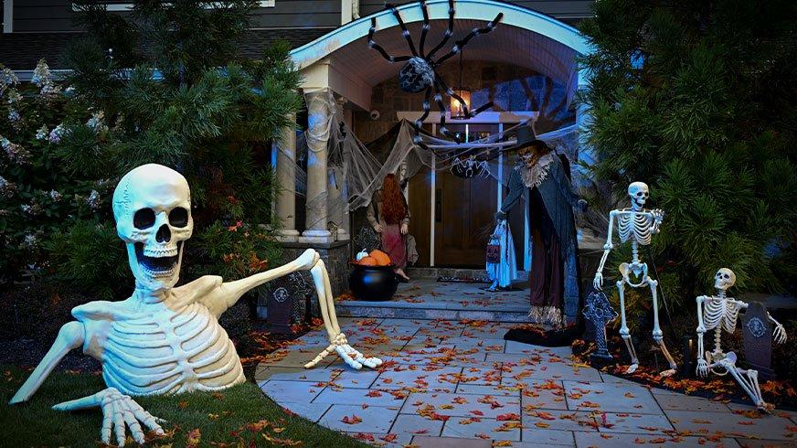 Front porch decorated with a some posable skeletons, animatronics, spiders and Giant Rattles the Groundbreaking Skeleton