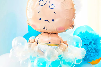 A baby-shaped balloon surrounded by clear latex balloons.