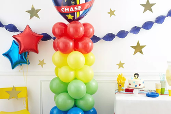 A multi-colored balloon column with a Paw Patrol balloon on top.