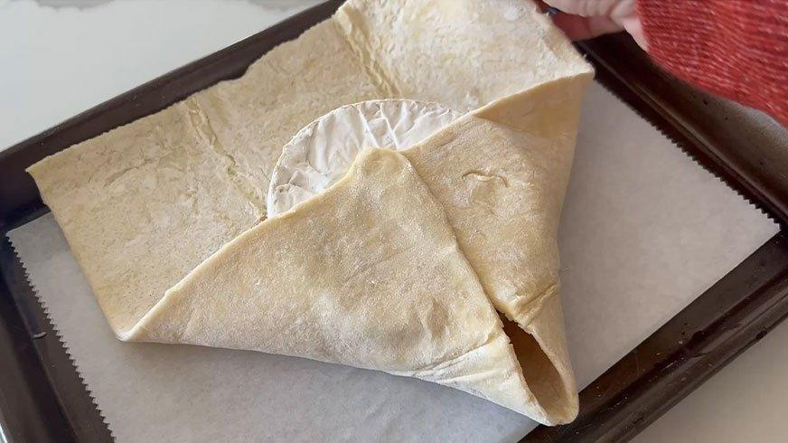Folding pastry dough over cheese.