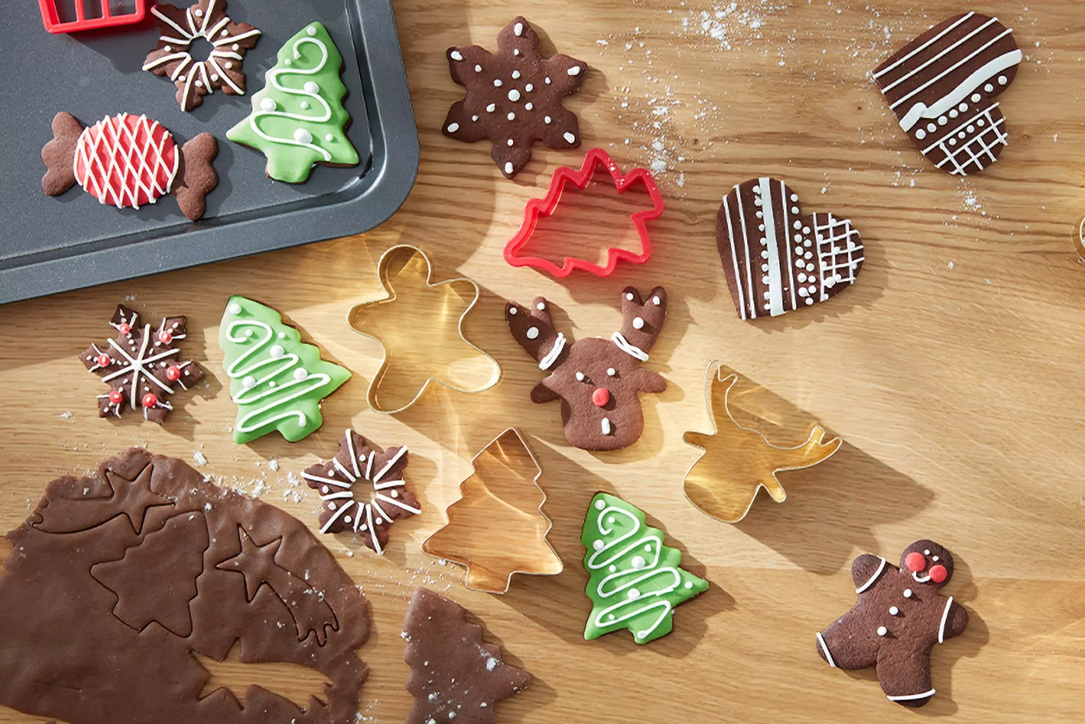 Świąteczne ciasteczka czekoladowe z Pepco w kształcie choinek, reniferów i gwiazdek z kolorowymi dekoracjami oraz foremki do wycinania.