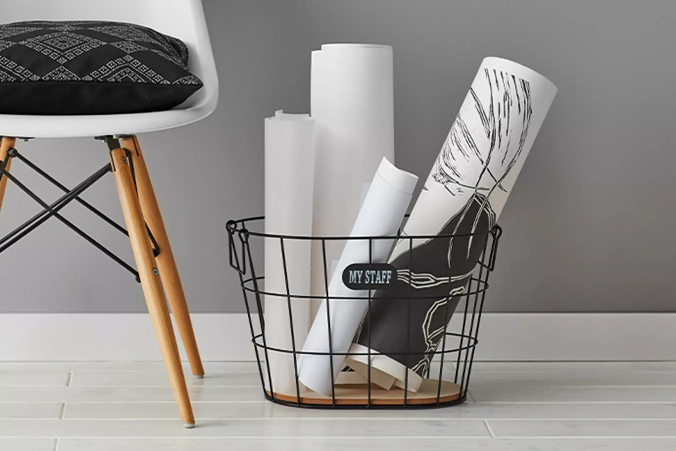 Coș metalic negru de la Pepco cu postere albe și un scaun modern alături, creând un decor minimalist de interior.