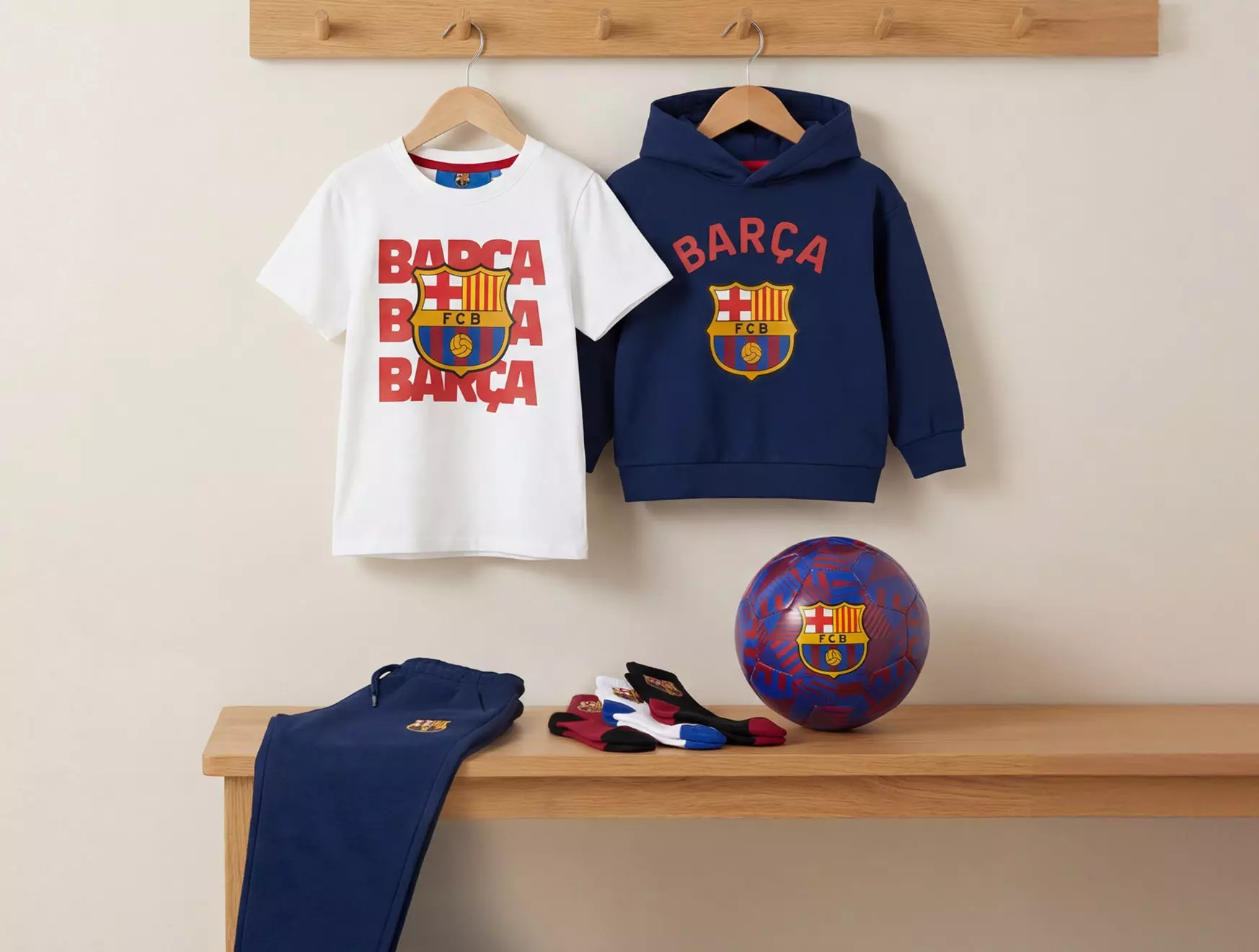 Kolekcja FC Barcelona w Pepco - koszulka, bluza z kapturem, spodnie, skarpetki i piłka z logo klubu piłkarskiego.