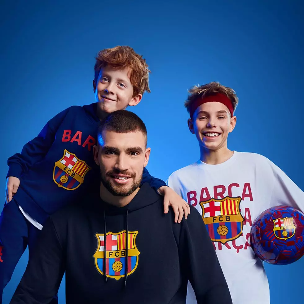 Kolekcja odzieży Pepco z motywem FC Barcelona - bluzy i koszulki z herbem klubu, obok piłka w barwach drużyny.