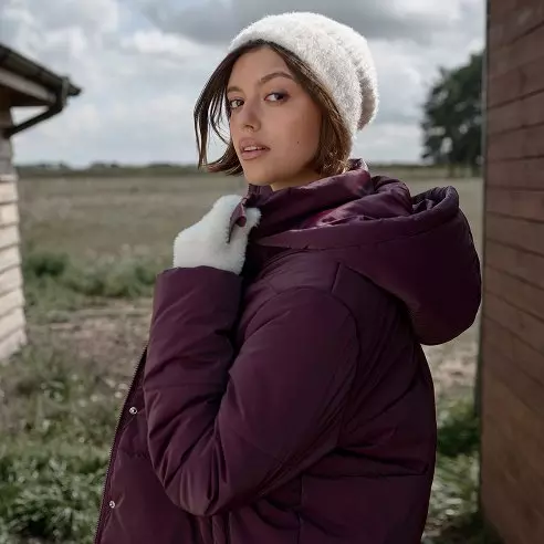 Mujer con gorro beige y chaqueta acolchada morada de Pepco en exterior.