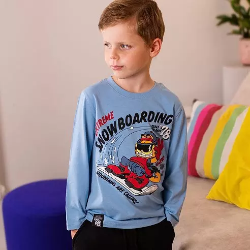 Bambino con maglia azzurra Pepco con stampa snowboard e pantaloni neri.