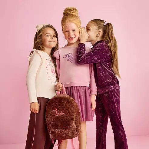 Tri dievčatá v Pepco oblečení s Barbie motívmi sa smejú a šepkajú si navzájom.