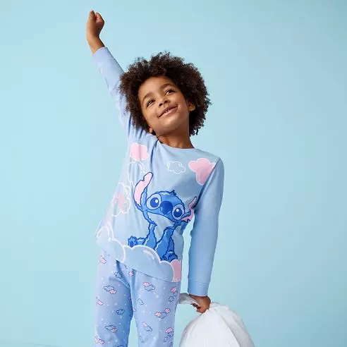 Criança a usar pijama Pepco azul com personagem Stitch da Disney, num gesto alegre.