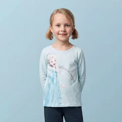 Bambina sorridente indossa una maglia Pepco azzurra a maniche lunghe con stampa di Elsa di Frozen.
