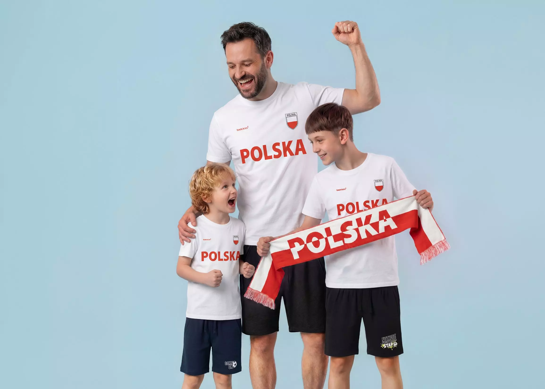 Mężczyzna i dwóch chłopców w białych koszulkach Pepco z napisem POLSKA, trzymający szalik kibica.