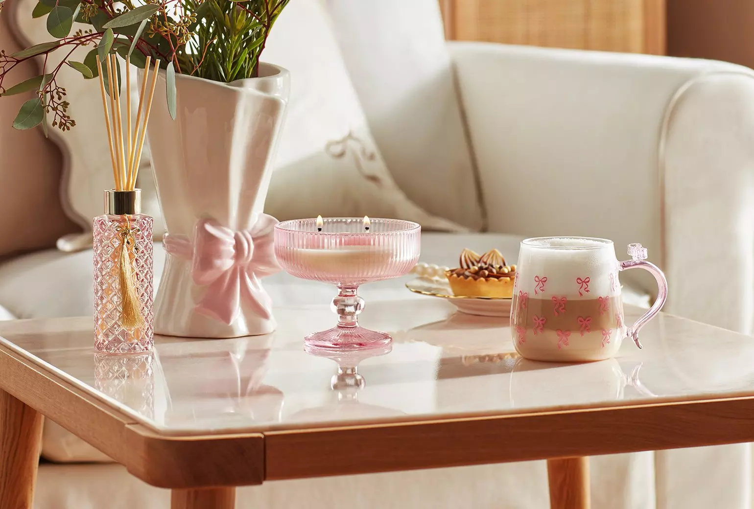 Kolekcja dekoracji domowych Pepco w różowych odcieniach - dyfuzor, wazon z kokardą, świeca i kubek z wzorem kokardek.