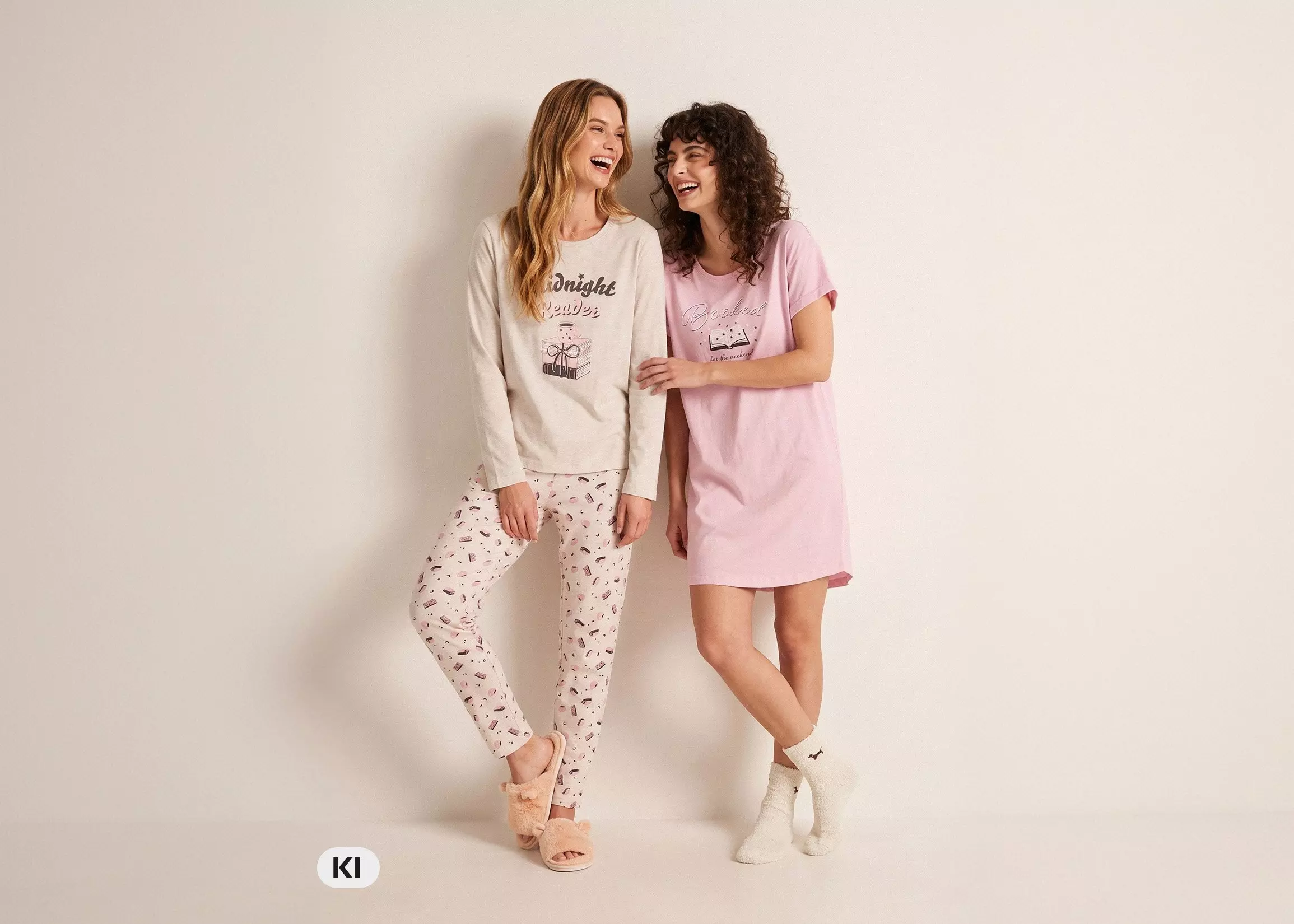 Zwei lachende Frauen in Pepco Schlafanzügen, eine im Pyjama-Set, die andere im rosa Nachthemd.