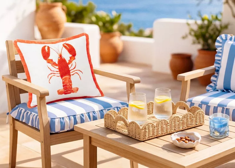 White cushion with red lobster design on wooden garden chair with blue striped seat cushion.