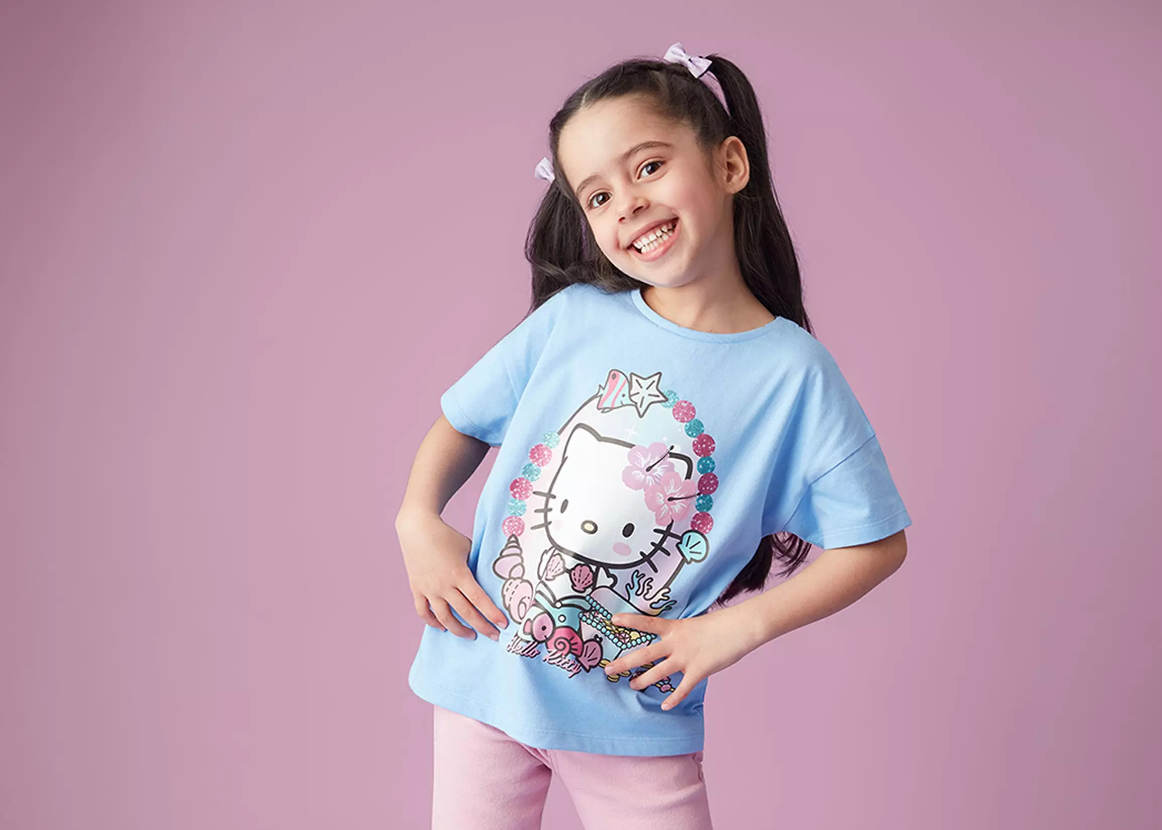 Smiling girl wearing Pepco blue Hello Kitty t-shirt with pink hair bows.